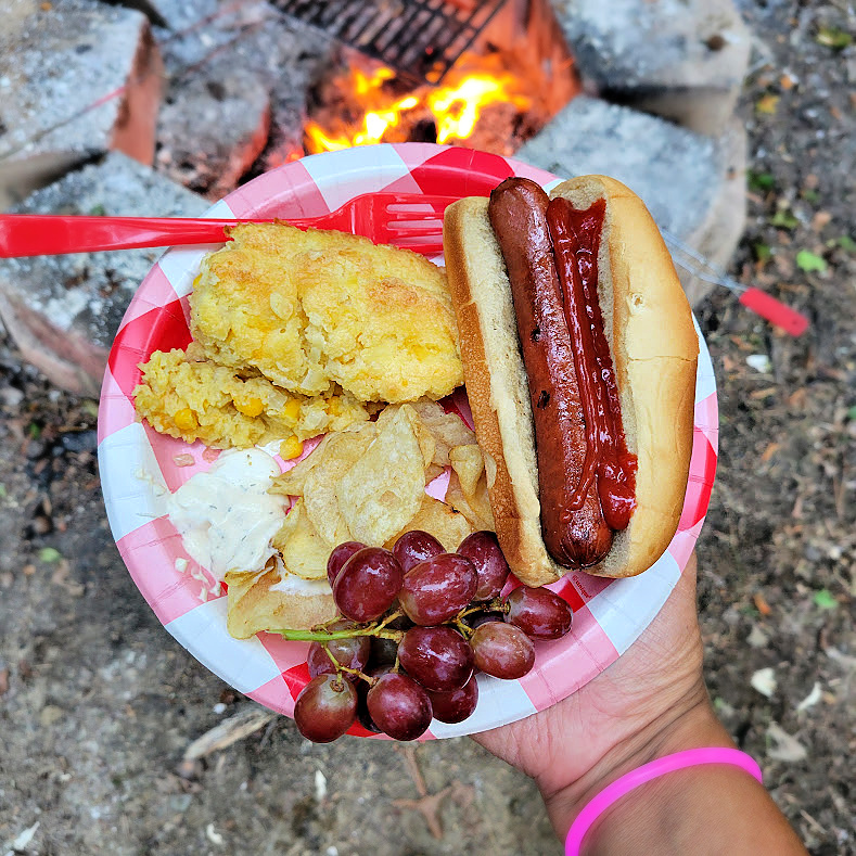 corn soufflé with a campfire hot dog, chips and dip, and grapes