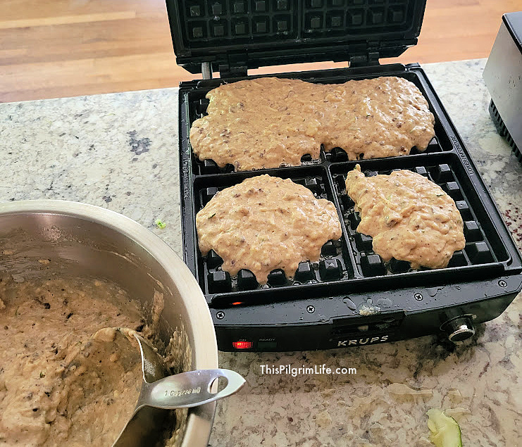 Filling the waffle maker with chocolate chip zucchini waffle batter