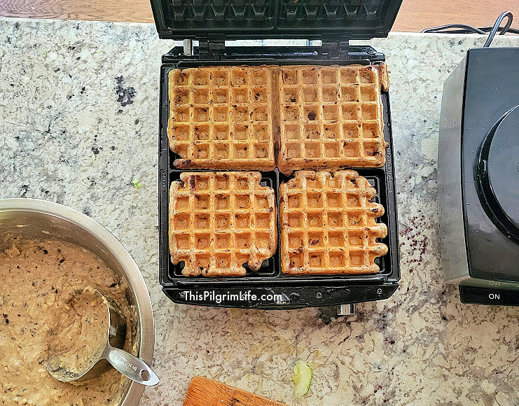 Chocolate chip zucchini waffles cooking in a waffle maker